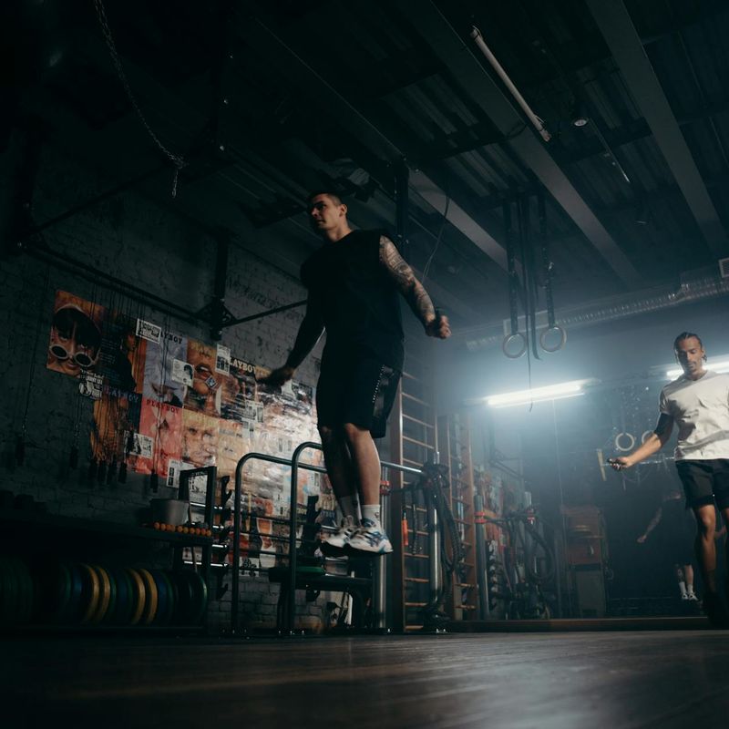 Person hands holding a jump rope in a dark gym.